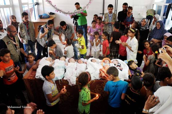 In una delle scuole dell'UNRWA si celebra, una settimana dopo, la nascita di alcuni bambini appartenenti a famiglie di sfollati. Gaza, 19 agosto 2014, foto di Mohammed Talatene.